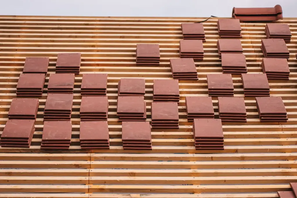 Tejado en construcción con tejas cerámicas apiladas sobre los rastreles